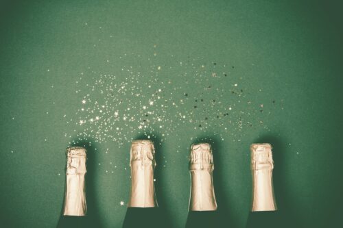 Bottles Of Champagne With Gold Glitter And Space For Text On Gre